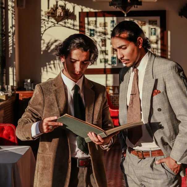 Elegantiški vyrai peržiūri Rūko baro meniu stilingoje aplinkoje